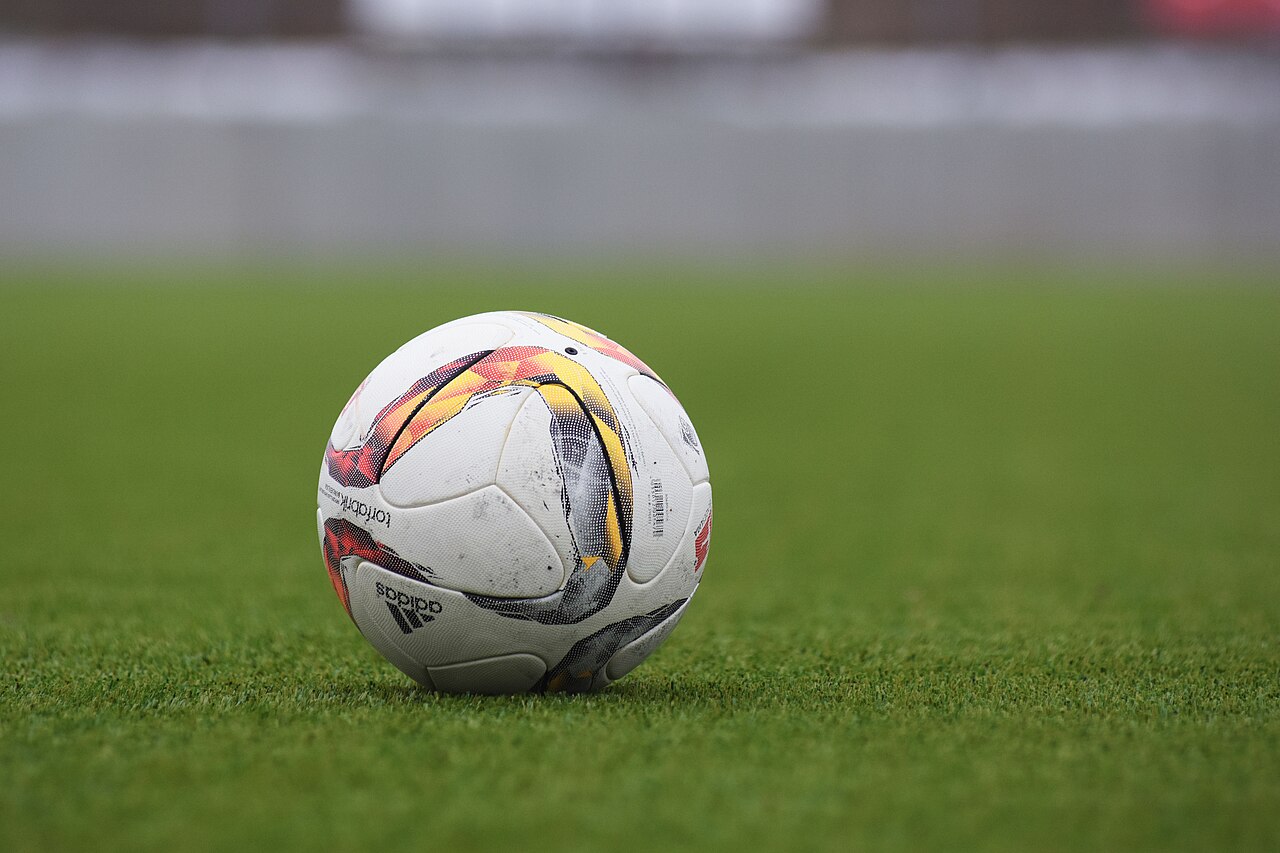 Piłka futbolowa na trawiastym boisku. Zdjęcie poglądowe, nie przedstawia meczu Naki Olsztyn z Polonią Pasłęk.